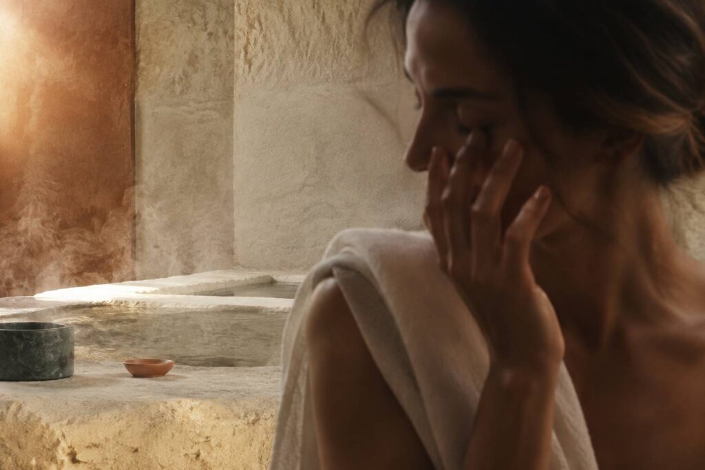 Femme au profil apaisé effleurant le contour de son œil dans une ambiance de soin minérale